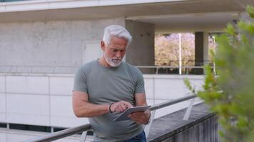Senior businessman using digital tablet near modern building outdoors video