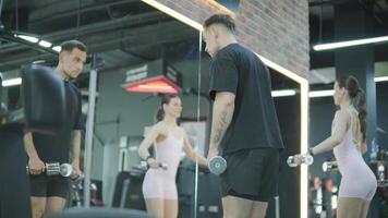 Man and woman doing fitness exercises in gym. Strength, endurance and training focus in modern fitness center 25 video