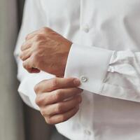 A man adjusting his cuff on his white shirt photo