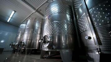 A happy successful farmer or winemaker is walking in the middle of wine tanks and checking a fermentation grade of high quality wine production in a modern winemaking facility or winery. 8 video