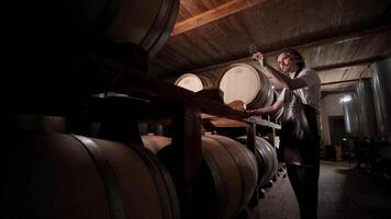 Authentic shot of successful male sommelier is tasting a flavor and checking white wine quality poured in transparent glass in a wine cellar. 19 video