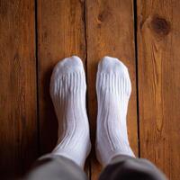 A person wearing white socks standing on a wooden floor photo