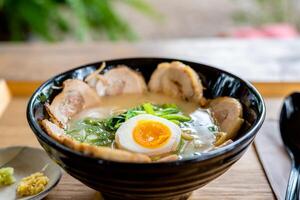 Japanese noodle soup ramen with egg and pork in black ramen bowl for asian food concept. photo