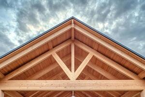 Wooden roof beams supporting modern building against cloudy sky photo