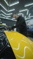 Technician Washing Hood of Yellow Car with Foam and Spray video