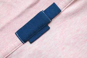 A close up of a pink shirt with a blue tag photo