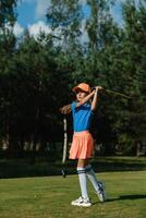 Young girl practicing golf swing on a sunny day at a green course surrounded by trees photo