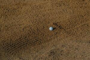 Golf ball resting on sand in a golf course bunker, highlighting the challenge players face during a round photo