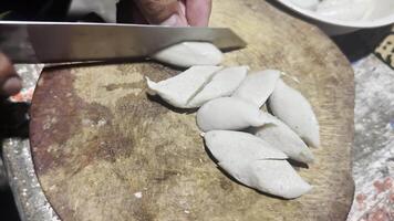A person cutting up some dumplings on a wooden board video