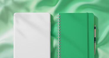 Green notebook mockup with pen and smartphone on silk photo