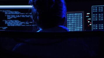 Young woman working at night with coding interfaces and binary system on display. video