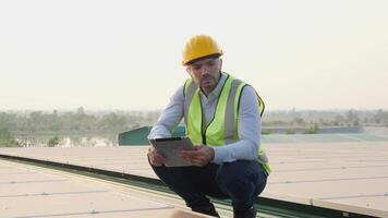 Engineer or construction worker wearing a yellow hard hat and reflective vest using tablet for rooftop. video