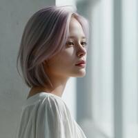 Young woman with light hair gazing out a window in soft light photo