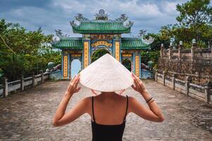 Woman traveler visiting at Linh Ung Pagoda temple, translation from Chinese character. Tourist with Vietnamese hat traveling in Da Nang city. photo