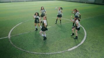 A group of six young women performing a dance routine on a soccer field. They are dressed in matching outfits, showcasing energetic movements video