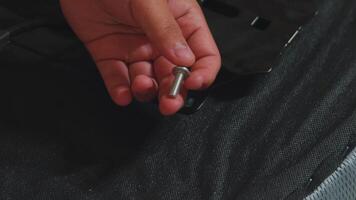 Hand Holding a Metallic Screw Above a Black Surface video
