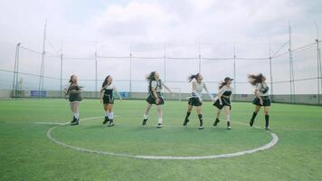 A dynamic group of six dancers performing energetically on a sports field, with a blurred motion effect. They are dressed in stylish outfits, showcasing a lively atmosphere under a cloudy sky. video
