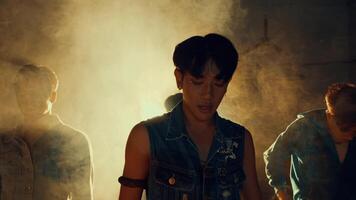 Three young adults dancing in a dusty, backlit environment, expressing freedom and youthfulness during the night video