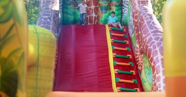 Children Playing on Inflatable Slide at Outdoor Playground video