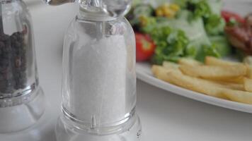table with salt and pepper shakers, salad, fries, and other food video