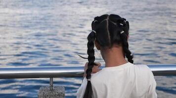 Child gazes at rippling water from a dock video