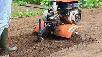 Latin farmer woman plowing soil with orange cultivator video