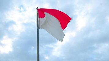 Indonesian flag Sang Merah Putih waves atop a tall pole under drifting clouds, reflecting freedom, unity, and the cultural spirit of Indonesia. video