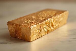 A shimmering bar of gold resting on a smooth marble surface, reflecting warm light. photo