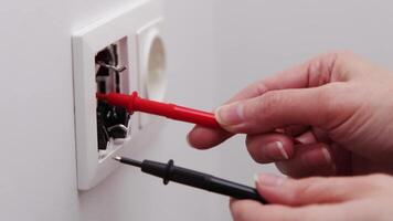 Close-up of a person using multimeter probes to test an electrical outlet, highlighting safety and electrical diagnostics in home maintenance. video