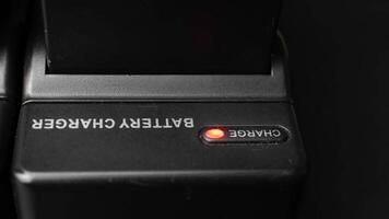 Close-up of Black Battery Chargers Charging Batteries with Red LED Indicators in a Dark Environment video
