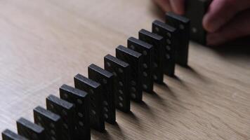 Close-up of Hands Setting Up Black Dominoes on Wooden Table for Strategic Domino Game Session video