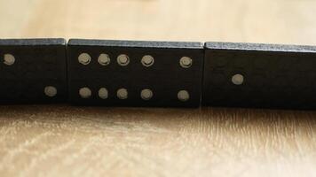 Close-up of Black Domino Tiles Lined Up on a Wooden Surface in Natural Light Highlighting Texture video
