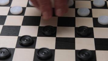 Close-up of a Hand Moving Checker Piece on Classic Black and White Checkers Board in Indoor Setting video