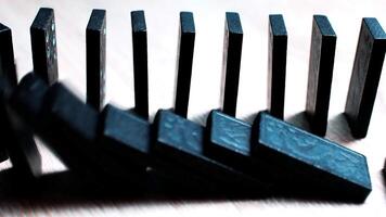 närbild av svart domino faller i sekvens på trä- yta som visar kedja reaktion dynamik video