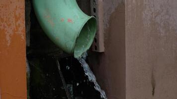 Close-Up of Water Flowing from Green Rain Gutter Pipe in Urban Environment during Rainy Weather video
