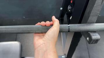 A close up of a Caucasian hand gripping a barbell, symbolizing strength, fitness, and weightlifting in a gym environment video