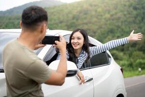 Joyful Adventure. Young woman enjoying a car ride while being photographed. photo