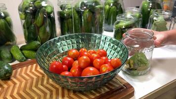 A kitchen scene with fresh tomatoes, pickling cucumbers, and glass jars, perfect for canning and preserving enthusiasts video