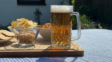 A refreshing glass of beer with snacks on a sunny day, perfect for picnics, barbecues, and summer gatherings video