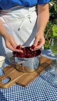 A person prepares fresh cherries in a colander on a sunny day, evoking summer, health, and home cooking Caucasian adult culinary arts video