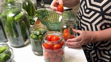 A woman prepares jars of pickled cucumbers and tomatoes, highlighting home canning, preservation, and sustainable living focus on DIY techniques video