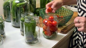 A woman prepares jars of pickled vegetables, including cucumbers and cherry tomatoes, highlighting home canning, preservation, and DIY food projects video