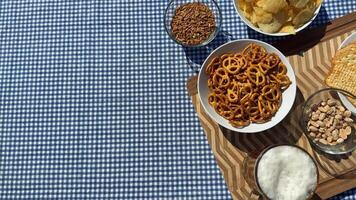 A variety of snacks including pretzels and chips on a checkered tablecloth evoke picnic vibes and casual gatherings video