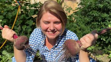 Caucasian woman in her 30s joyfully harvesting beets in a lush garden, celebrating organic farming and sustainability video