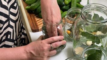 A person prepares pickles with fresh cucumbers, garlic, and herbs, showcasing home canning and sustainable practices video