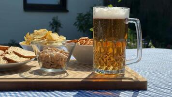 A refreshing beer mug sits on a table with snacks, perfect for Oktoberfest or summer gatherings, featuring pretzels and chips video