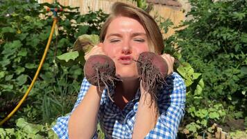 Caucasian woman in her 30s joyfully showcases freshly harvested beets in a lush garden, celebrating harvest season and sustainable farming video