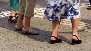 A group of diverse women wearing summer sandals, walking on a cobblestone street during a sunny day, highlighting casual fashion and urban exploration video