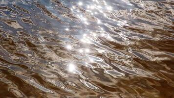 Sunlight reflecting and glittering on slow moving water surface video