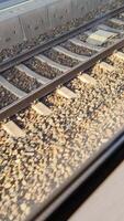 Fast passenger train speeding along railway tracks, passing gravel and concrete sleepers with blurred landscape and dynamic motion perspective. video